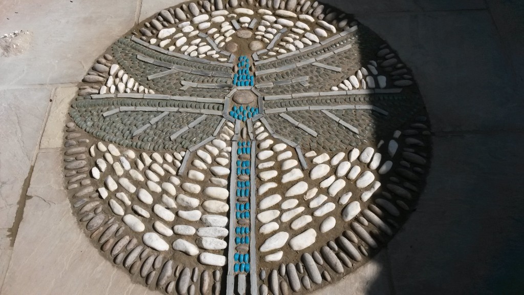 Completed dragonfly pebble mosaic set into garden paving