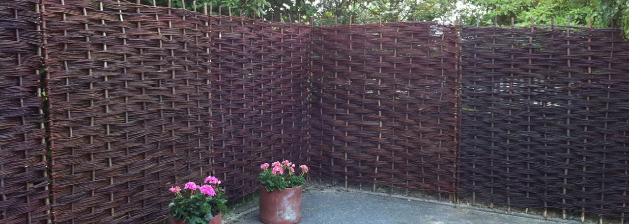 Woven timber garden fencing around a paved seating area