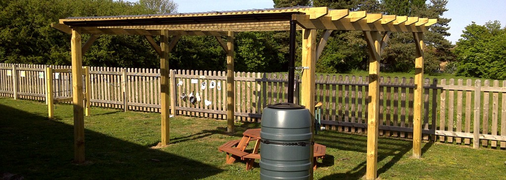 Timber pergola in a lawn beside a picket fence