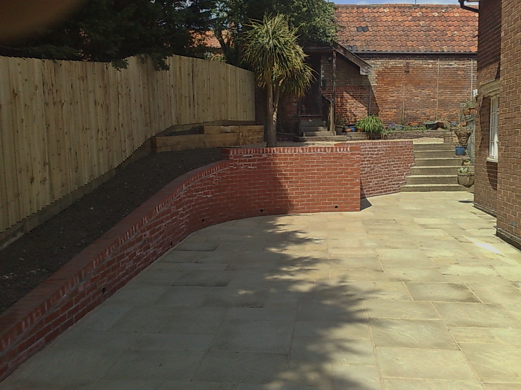 Paved terrace edged by a curved brick retaining wall