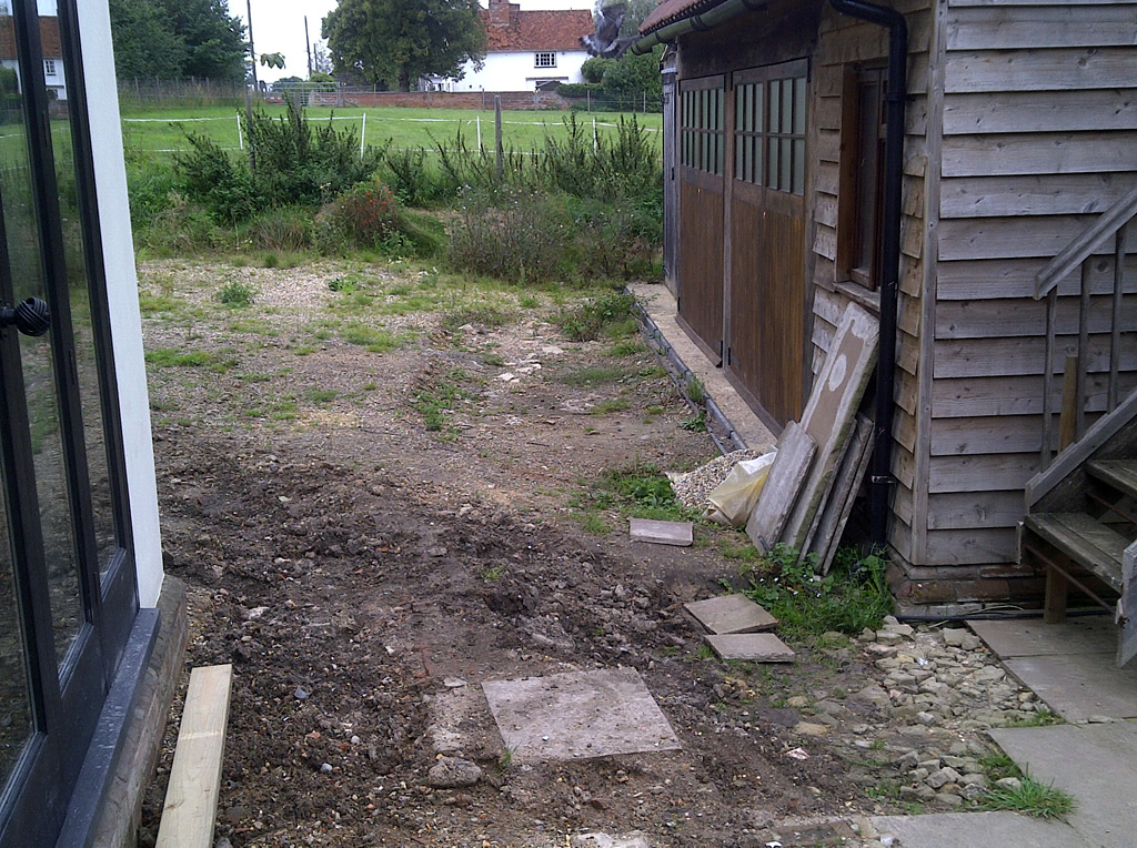 Uneven garden ground beside a timber outbuilding before landscaping