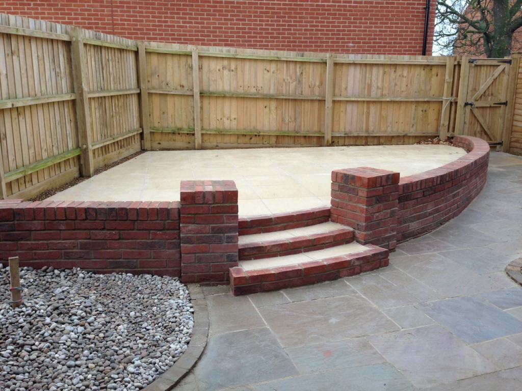 Raised patio with curved brick steps and retaining wall