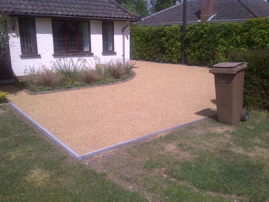 Finished gravel driveway beside a house and hedged boundary