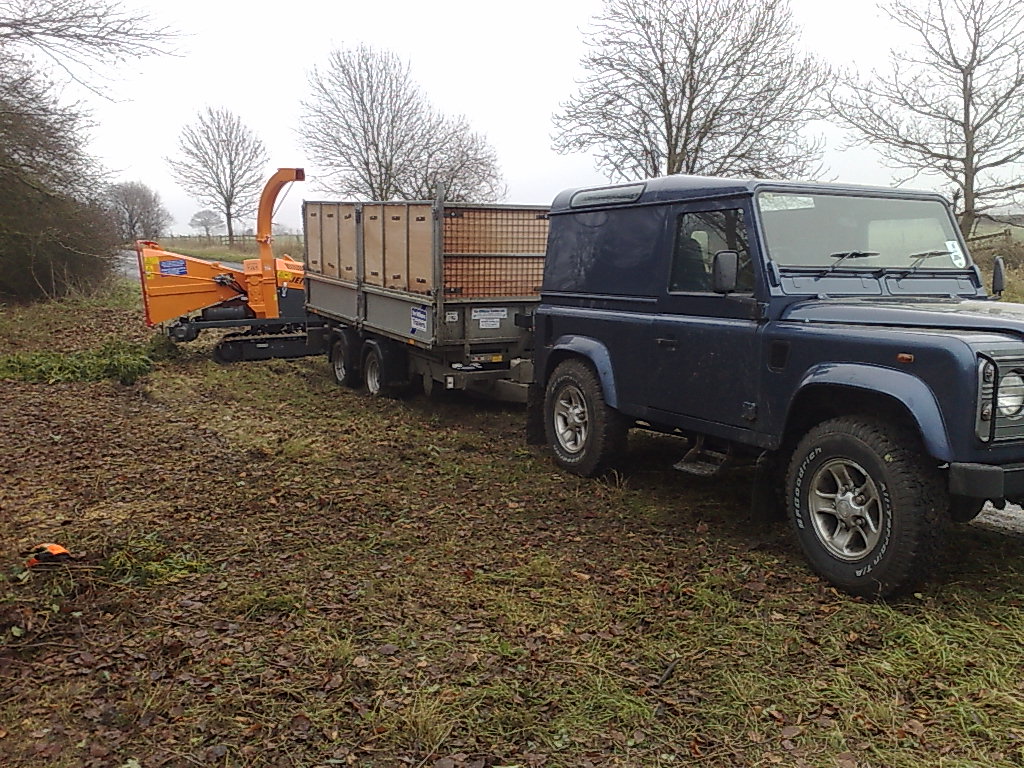 Work vehicle and chipper during roadside vegetation clearance