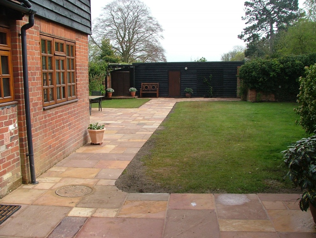 Completed stone patio beside a lawn and planted borders
