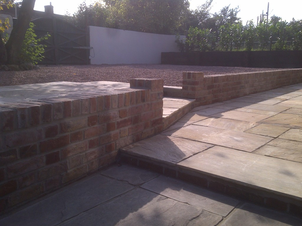 Gravel courtyard and stone paving divided by brick retaining walls