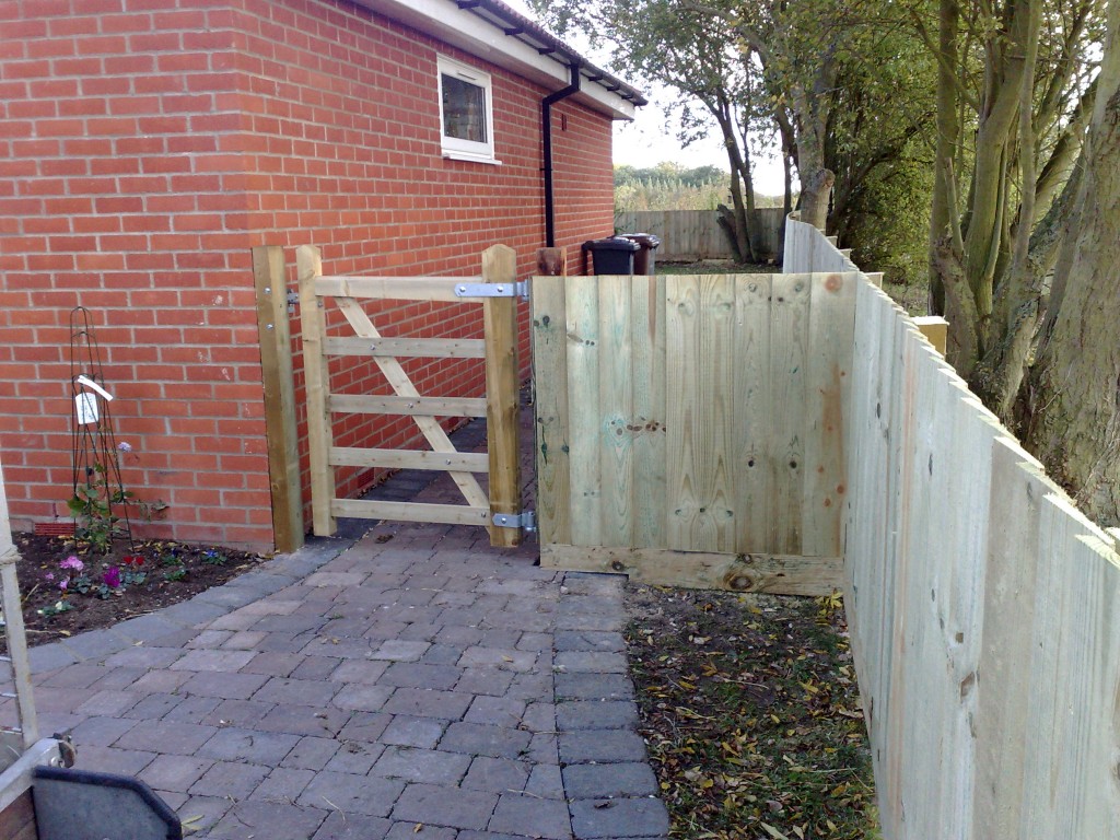 Timber pedestrian gate beside a house and boundary fence