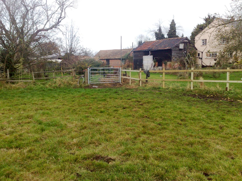 Aluminium field gate beside timber post-and-rail fencing