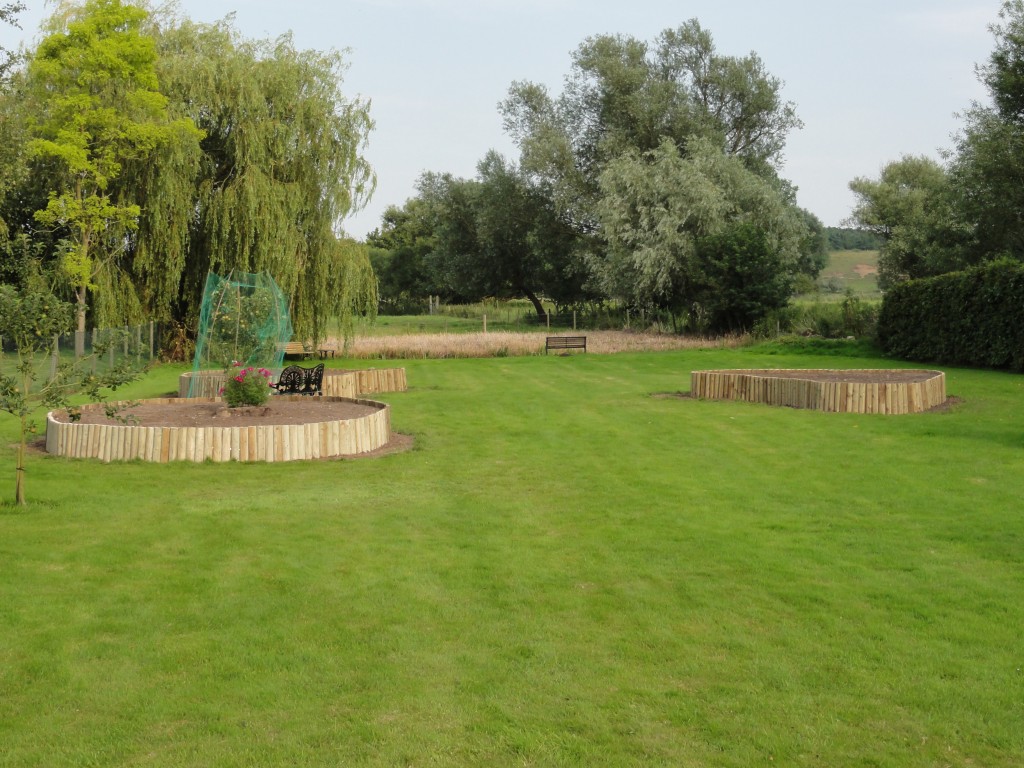 Curved timber-edged raised beds set within a garden lawn