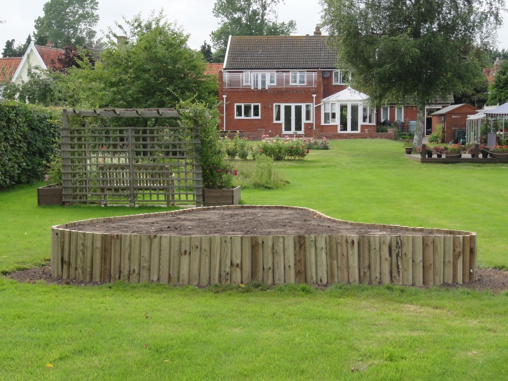 Curved timber-edged raised beds set within a garden lawn