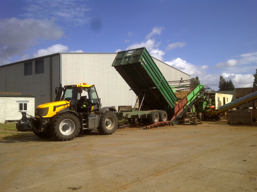 Tractor and tipping trailer transporting harvested crops