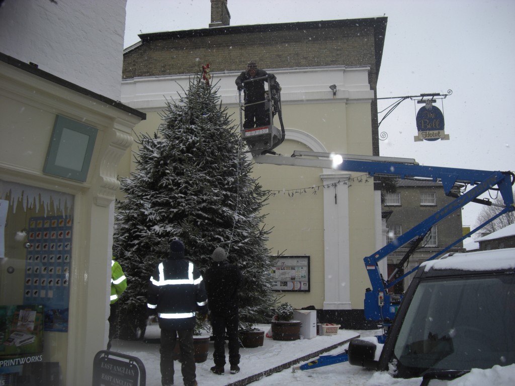 Cherry picker beside a large decorated outdoor Christmas tree
