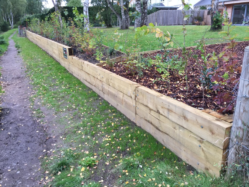 Completed timber sleeper retaining wall beside a garden path